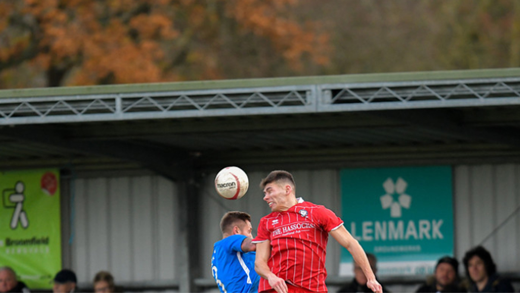 Hassocks forward Liam Benson challenges for a header against Peacehaven & Telscombe