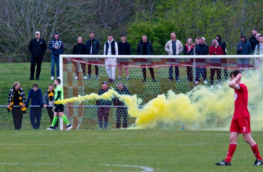 Hassocks goalkeeper Alex Harris removes a flare let off by Littlehampton Town fans during the Sussex Principal RUR Charity Cup semi final at the Beacon