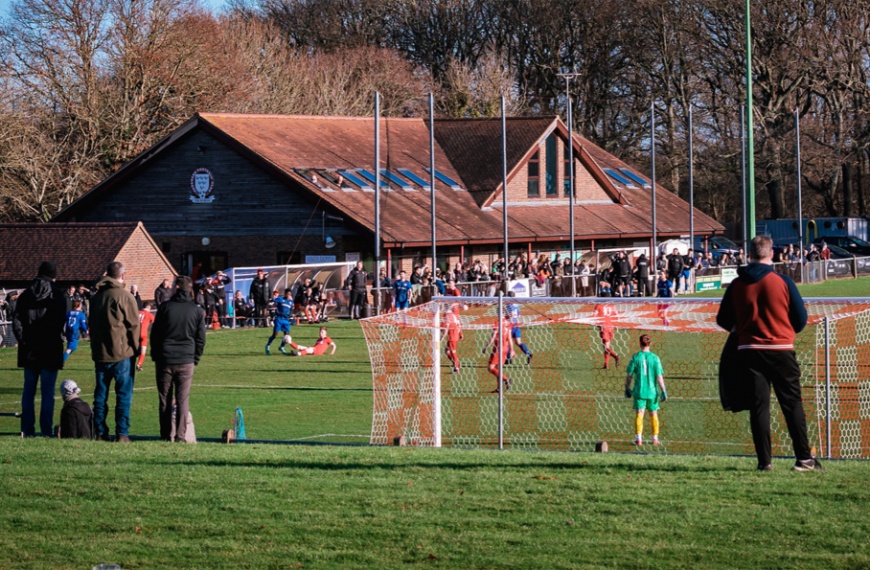 Hassocks fans watch a game from the bank with the Beacon clubhouse in the background