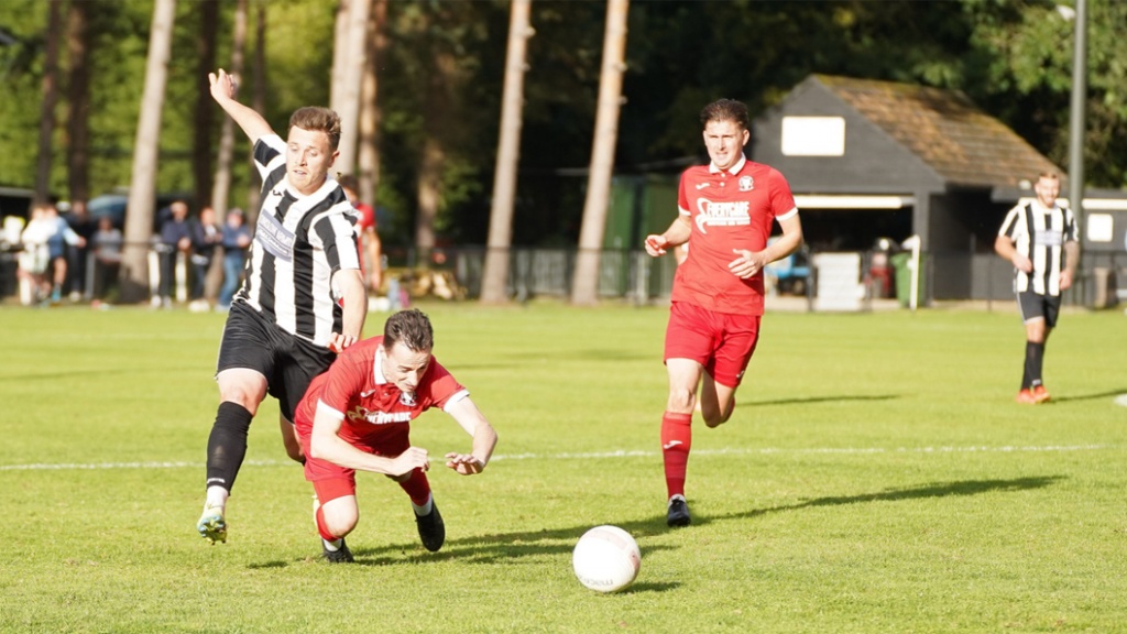 Hassocks defender Harvey Blake goes to ground under a heavy tackle from a Loxwood player