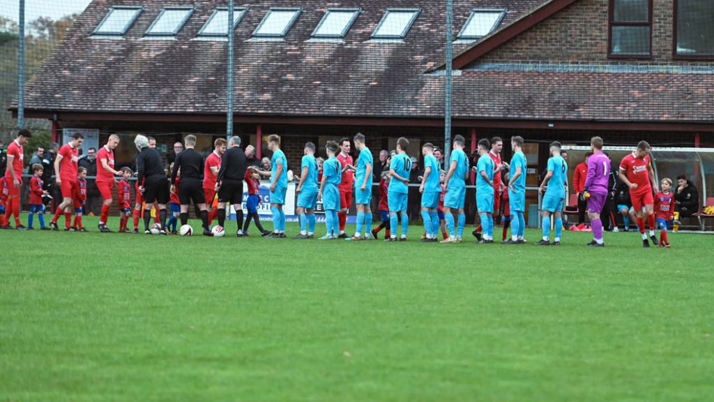 The players of Hassocks and Saltdean United shake hands