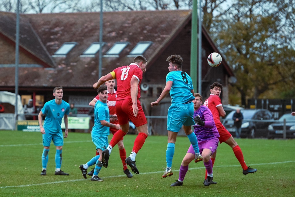 Alex Bygraves rises to win a header for Hassocks against Saltdean United