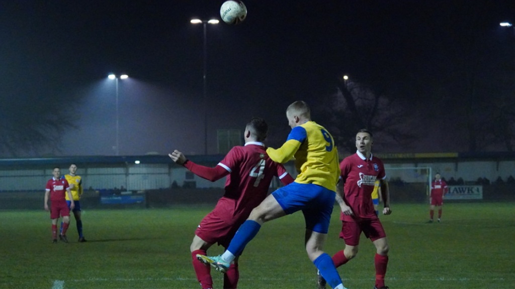 Hassocks midfielder Mike Williamson challenges for a header against Eastbourne Town