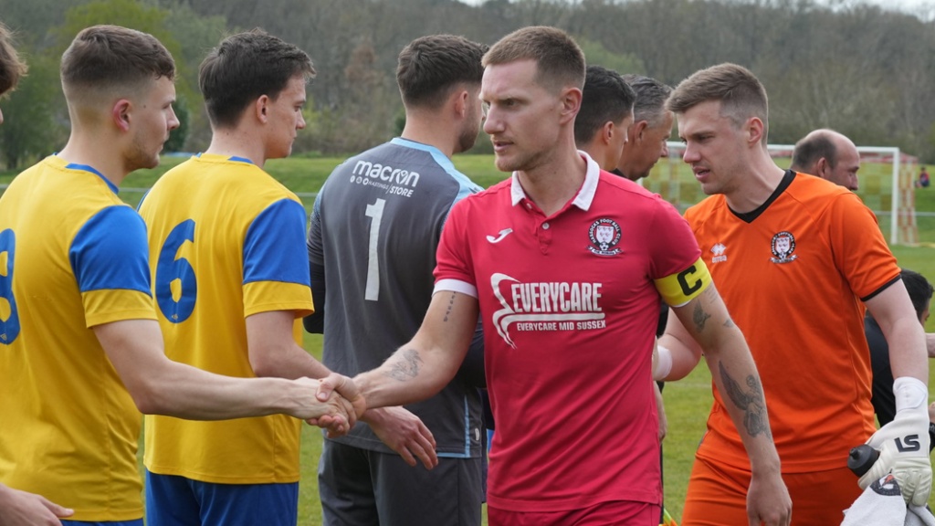 Hassocks captain Alex Bygraves and goalkeeper James Shaw shake hands with Eastbourne Town players