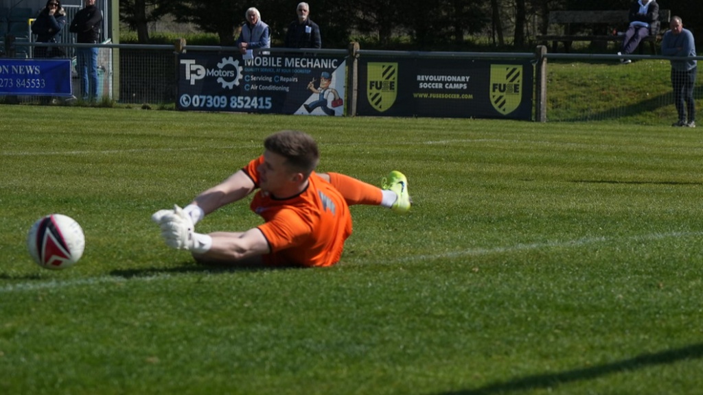 Hassocks goalkeeper James Shaw makes a sprawling save against Eastbourne Town