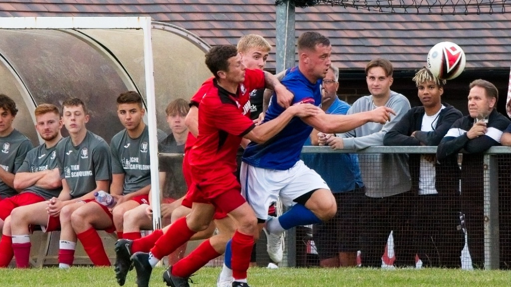 Mike Williamson of Hassocks challenges a Burgess Hill Town player