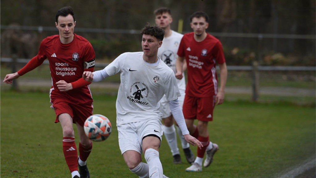 Hassocks captain Harvey Blake challenges a Eastbourne United player 